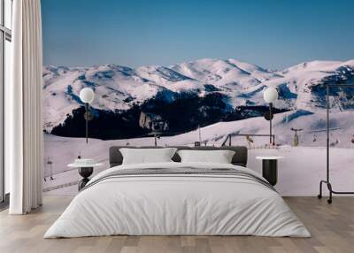 Panoramic view over the ski slope Poiana Brasov ski resort in Transylvania, Pine forest covered in snow on winter season,Mountain landscape in winter with the Bucegi Mountains in the background. Wall mural