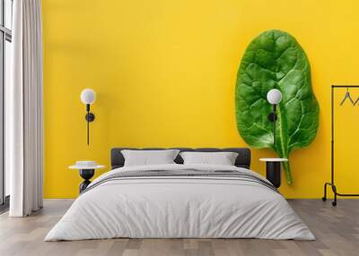 Single spinach leaf on bright yellow background Wall mural