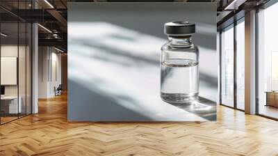 Transparent glass vial with clear liquid on a shadowed surface Wall mural