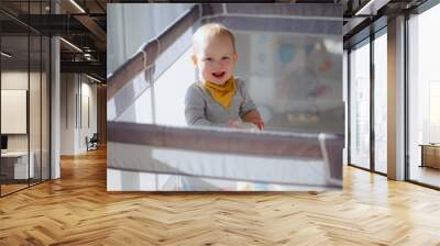 Cute laughing baby boy toddler playing in playpen, Adorable child having fun indoor, Portrait of little smiling kid standing in crib, Small toddler in playpen Wall mural