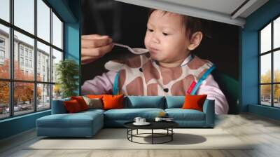 Asian toddler with dirty bib eat meal  by mom feed. Wall mural