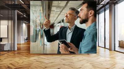 Business people meeting planning start up, talking, discussing ideas, brainstorming. Scrum master using sticky notes standing near planning board in modern office. Agile methodology, scrum concept Wall mural