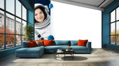 Space beautiful woman astronaut in space wearing astronaut space suit peeking out from behind a white blank banner,mockup,template. on earth blue background, copy space. Wall mural