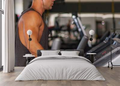 Young man in sportswear running on treadmill at gym.Handsome sport gym man running on the treadmill.Indoors shot. Wall mural