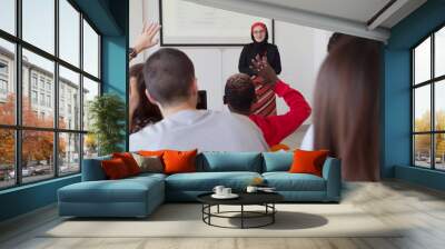 Female muslim professor explain lesson to students and interact with them in the classroom.Helping a students during class. University student being helped by female lecturer during class. Wall mural