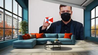 American man wear black formal and protect face mask, hold Wichita flag card isolated on white background. USA cities coronavirus Covid concept. Wall mural