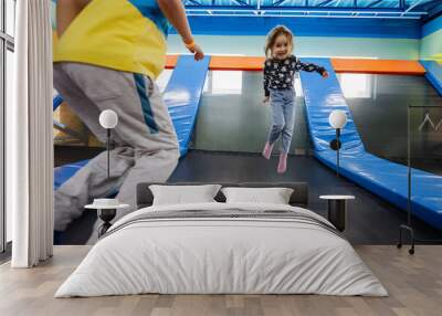 Brother with sister playing at indoor play center playground , jumping in trampoline. Wall mural