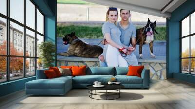 Couple in love with two dogs pit bull terrier on a walk. Wall mural