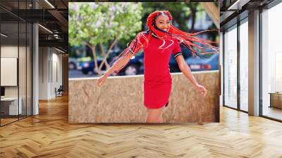 Cute and slim african american girl in red dress with dreadlocks in motion having fun on street. Stylish black model. Wall mural