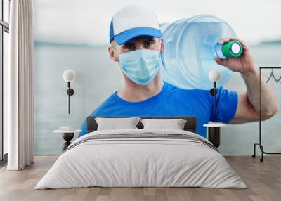 Delivery water man wear protective face medical mask during coronavirus pandemia. Wall mural