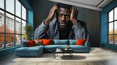 Depressed african american man sitting on a dark grunge background. Wall mural