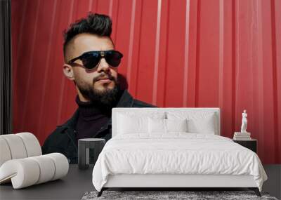 Fashion Arab man wear on black jeans jacket and sunglasses posed against red steel wall background. Stylish and fashionable arabian model guy. Wall mural