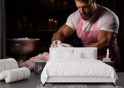 Masculine man pastry chef in white t-shirt and apron sprinkling pink marshmallow on cupcakes. Wall mural