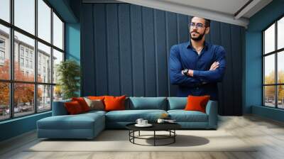 Middle eastern entrepreneur wear blue shirt, eyeglasses, against steel wall. Wall mural