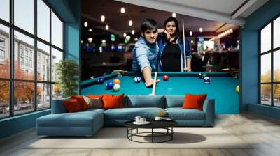 Stylish asian couple wear on jeans playing pool billiard on bar. Wall mural