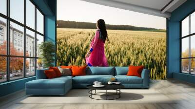 Tender indian girl in saree, with violet lips make up posed at field in sunset. Fashionable india model. Wall mural