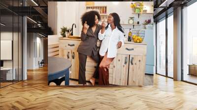 Two african american female friends women spending time at kitchen with wine. Black girlfriends  relaxing at home and eat chocolate. Wall mural