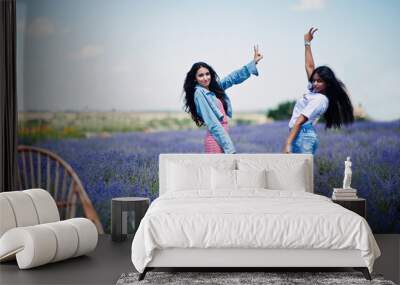 Two beautiful indian girls in purple lavender field. Wall mural