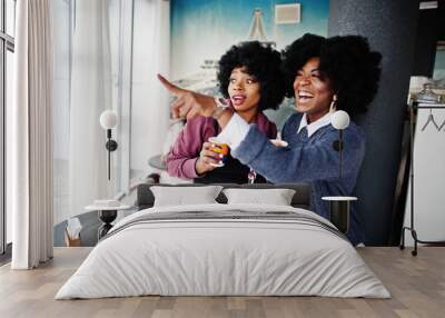 Two curly hair african american woman wear on sweaters with cups of tea posed at cafe indoor. Wall mural