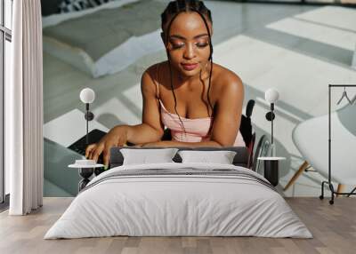 Young disabled African American woman in wheelchair at home working with laptop. Wall mural