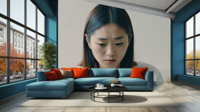 Close-up portrait of a young Japanese Asian woman immersed in the use of a smartphone, focusing on her expression and the interaction with the phone Wall mural