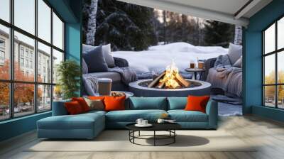 A serene outdoor winter celebration scene with a fire pit surrounded by cozy seating, warm blankets, and hot beverages. Wall mural