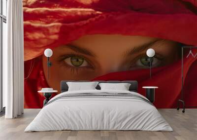 Portrait of a woman hiding her face behind red fabric, with only her green eyes visible Wall mural