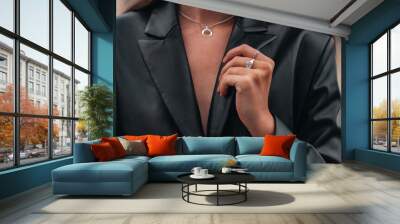 Female hands in a black stylish leather jacket and silver accessories on a female body. Jewelry and women's fashion Wall mural