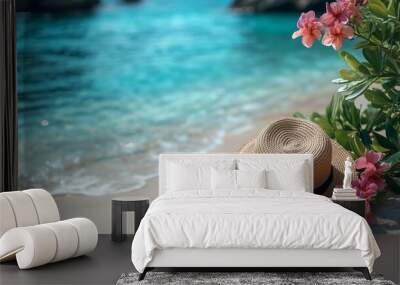 a straw hat adorned with vibrant pink flowers resting on white sand. Wall mural