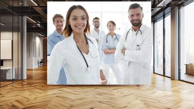 Attractive female doctor with medical stethoscope in front of medical group Wall mural