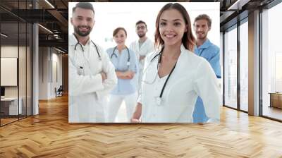 Attractive female doctor with medical stethoscope in front of medical group Wall mural