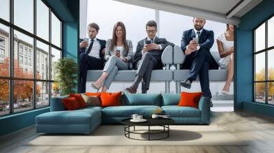 business colleagues with their smartphones sitting in the office hallway Wall mural