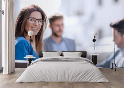 business woman sitting at a table on the background of colleagues Wall mural