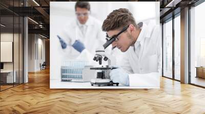 close up.the scientist looks through the microscope Wall mural