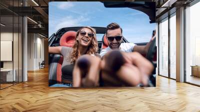 close up.young couple sitting in a convertible and pointing at y Wall mural