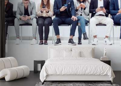 group of diverse young business people looking at their smartphone screens. Wall mural