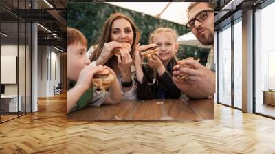 happy family eating burgers sitting at a table in a cafe Wall mural