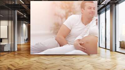 husband and pregnant wife lying on the bed in the bedroom. Wall mural