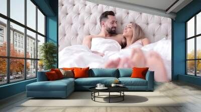 loving couple talking while lying on the bed Wall mural