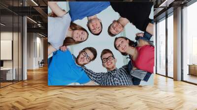 Low angle view of happy men and women standing together in a circle Wall mural