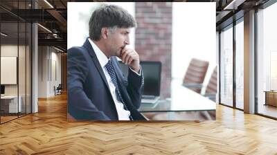 pensive businessman sitting at office desk in office Wall mural