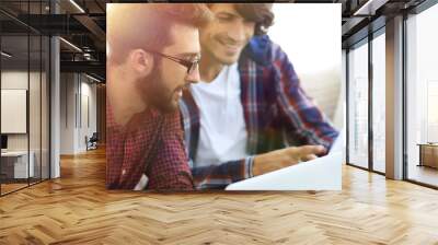 Portrait of two web designers discussing a project in front of a laptop Wall mural