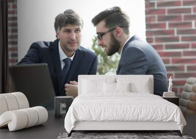 Two businessmen working together using laptop on business meeting in office Wall mural