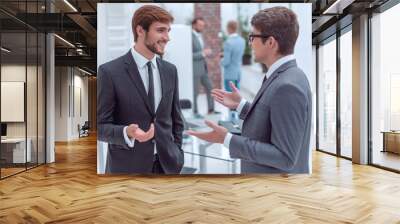 two young entrepreneurs talking standing in the office. Wall mural