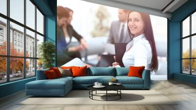 young business woman sitting in office at background business te Wall mural