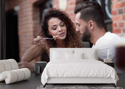 Young couple enjoying coffee at a street cafe and  laughing Wall mural