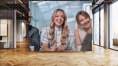 young employee enthusiastically tells something to her colleagues Wall mural