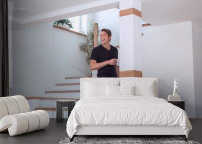 young man with a Cup of coffee standing in his new apartment Wall mural