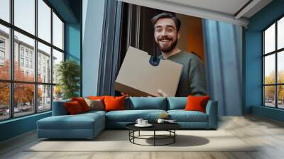 Happy man receiving a package at his door. Wall mural