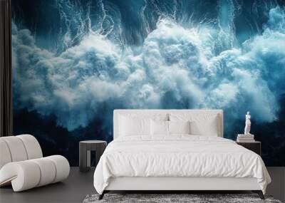 Aerial view of a massive wave crashing in the ocean, with white foam and blue water. Wall mural